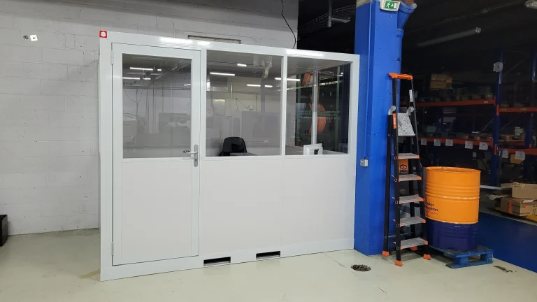 Cabine palettisable NOVOCAB vitrée sur socle acier, adossée au mur d’un entrepôt près des rayonnages