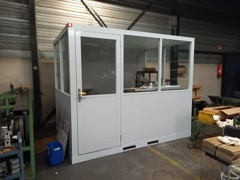 Bureau vitré préfabriqué entre les établis d’un atelier de mécanique
