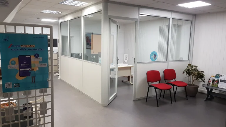 Bureaux vitrés en kit avec porte ouverte, à côté d’un espace d’attente aménagé de chaises rouges