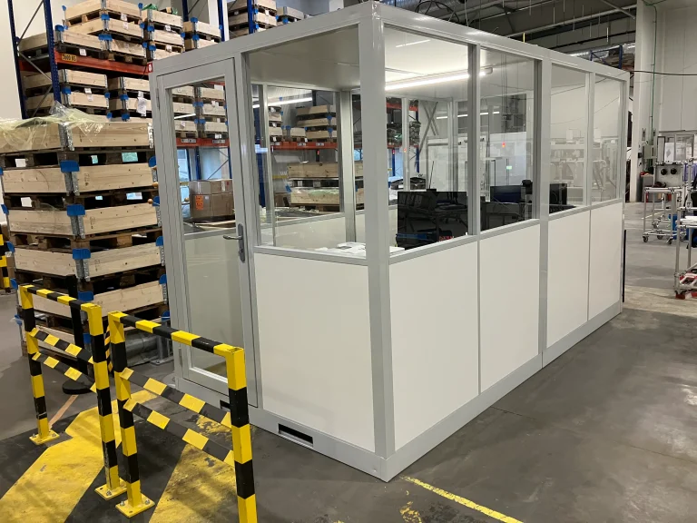 Cabine d’atelier vitrée protégée par des barrières de sécurité jaunes et noires en zone de production