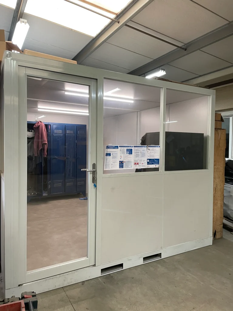 Cabine palettisable aménagée en vestiaire avec casiers, dans un bâtiment de stockage