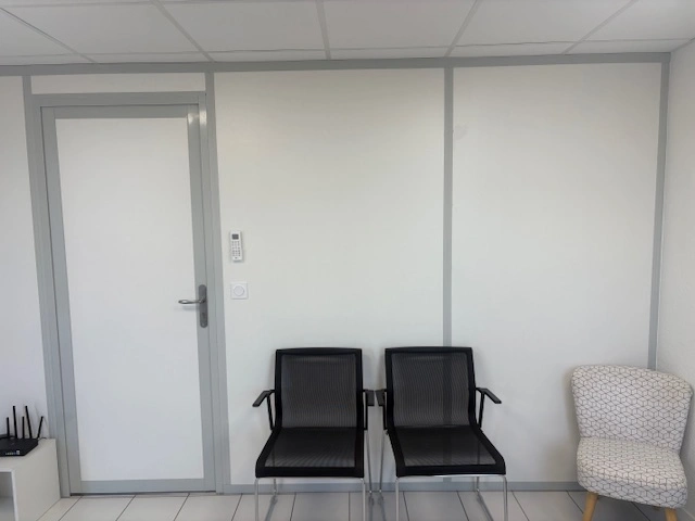 Cloison de bureau en kit pleine blanche avec porte, devant un espace d’attente